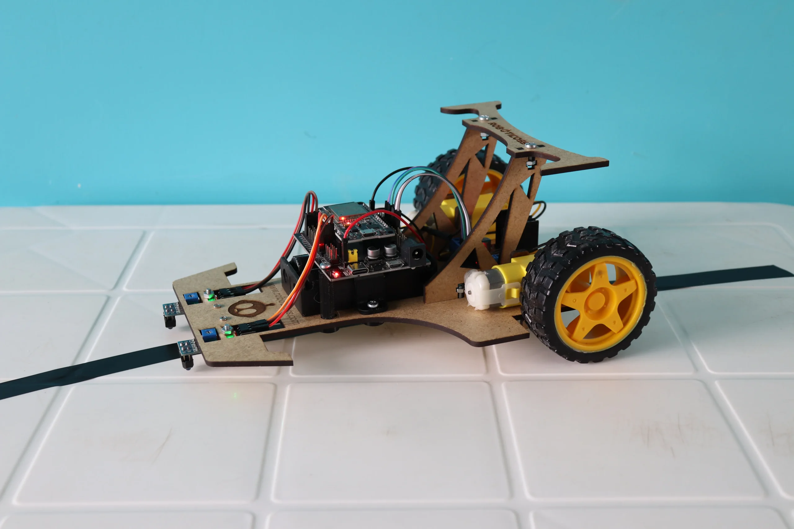Robot seguidor de línea armado sobre pista negra, parte de un kit de robótica educativo de Roboticoss